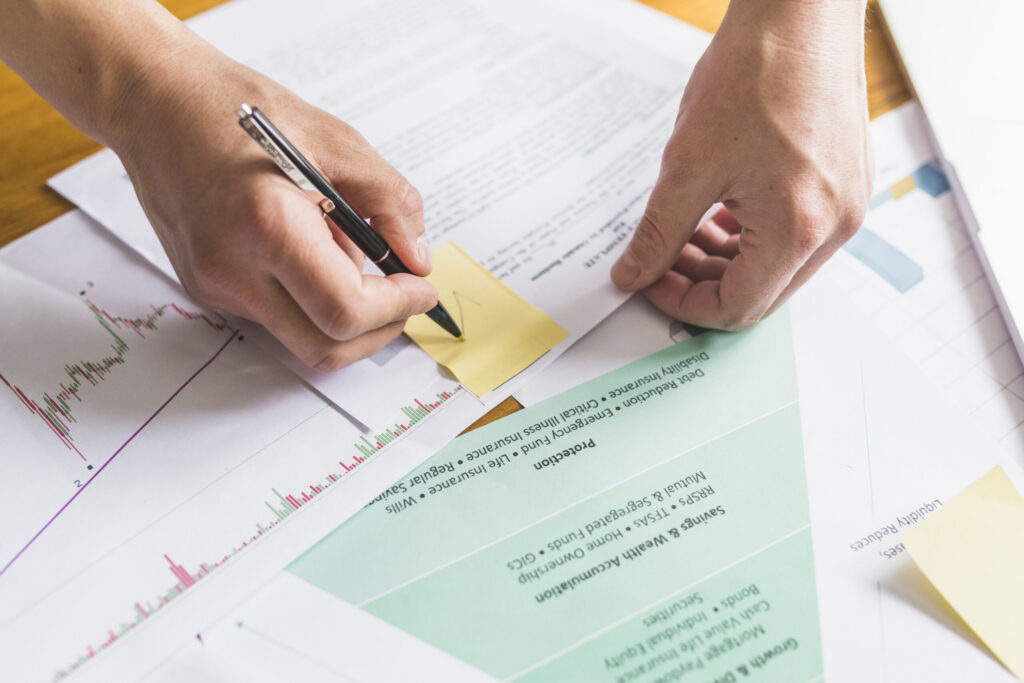 Hand checking items off a document with sticky notes