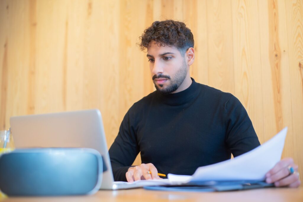 Contractor reviewing a SAM.gov registration and solicitation paperwork to bid the easiest government contracts to winA man working with documents using a laptop