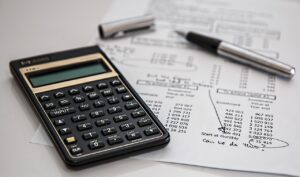 Calculator and pen on a printed ledger, the everyday tools behind DCAA compliance for a small contractor