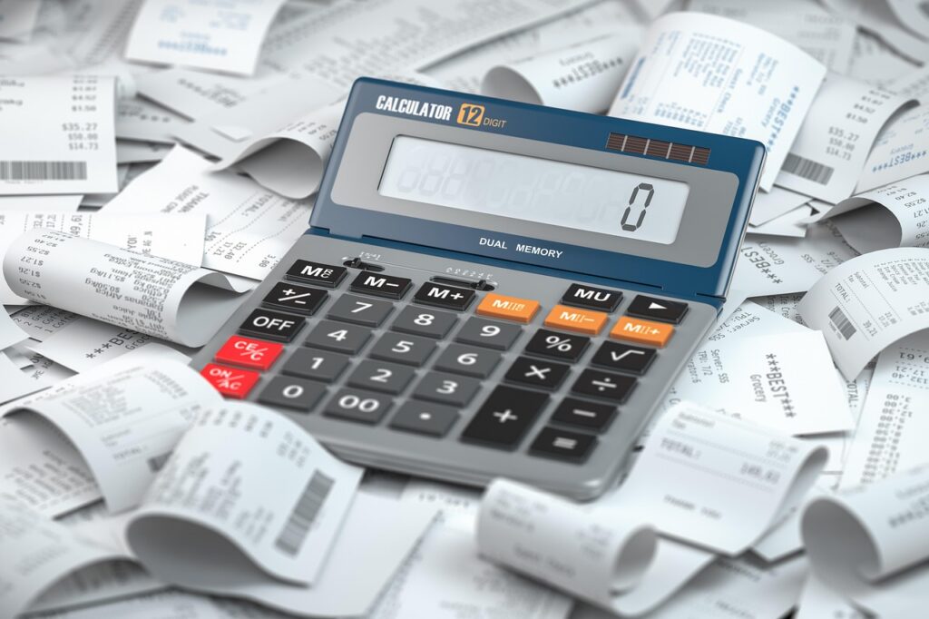 Calculator resting on a pile of business receipts, the raw material for separating allowable from unallowable costs