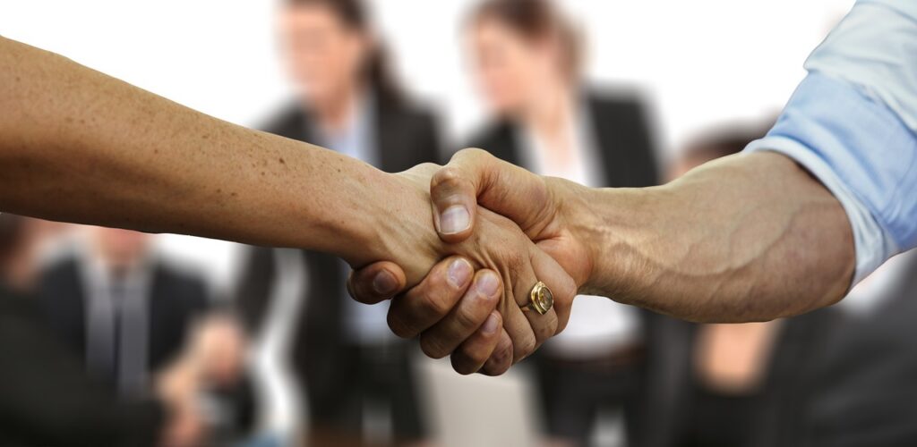 Two professionals shaking hands as a prime contractor and a small business agree on a government subcontracting deal