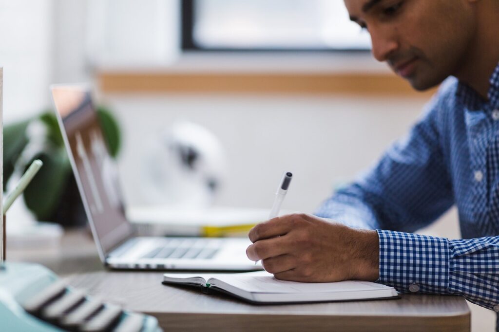 Small business owner taking notes on a laptop while researching which primes won recent federal awards