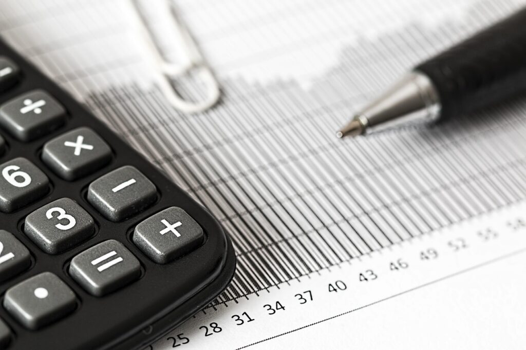 Calculator and pen on a payroll ledger, representing weekly certified payroll under the Davis-Bacon Act