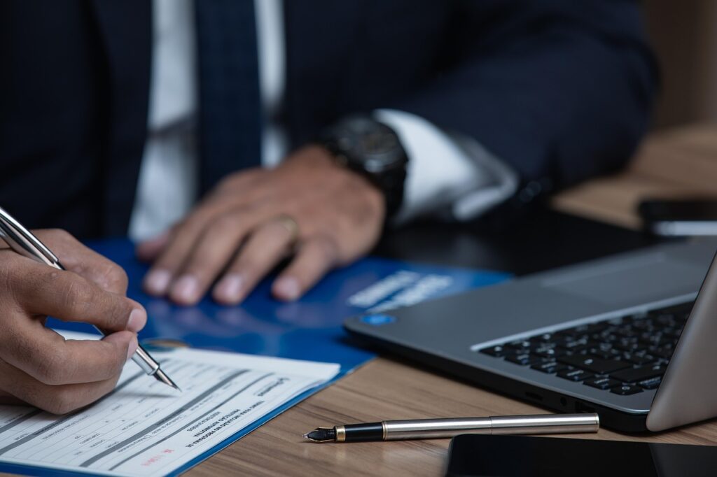 Contractor reviewing registration and certification paperwork at a laptop before approaching a prime