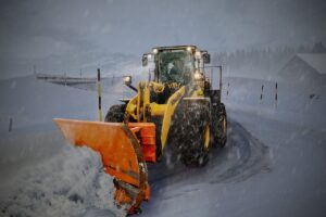 Wheel loader with a snow plow clearing a road, the kind of work covered by government snow removal contracts