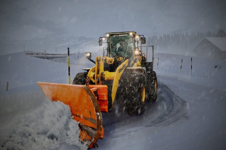 Wheel loader with a snow plow clearing a road, the kind of work covered by government snow removal contracts