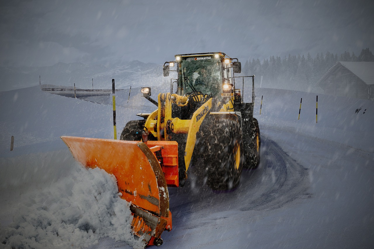 Wheel loader with a snow plow clearing a road, the kind of work covered by government snow removal contracts