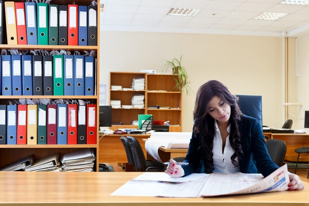 Woman business owner reviewing company records at her office desk, the kind of paperwork a WOSB certification application asks for